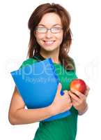 Young student girl is holding book and apple