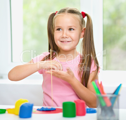 Girl is having fun while playing with plasticine