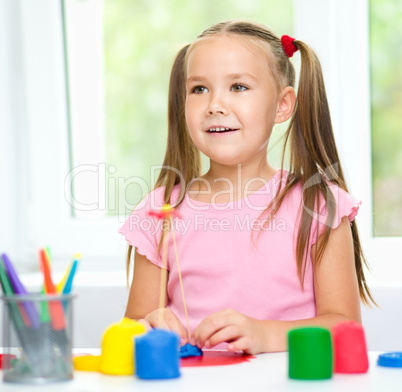 Little girl is playing with plasticine