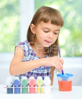 Little girl is painting with gouache