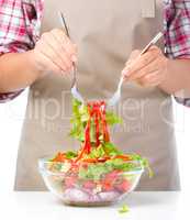 Cook is mixing salad