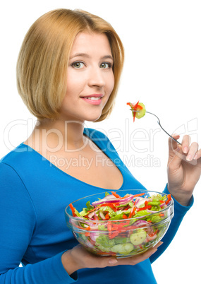 Young attractive woman is eating salad using fork