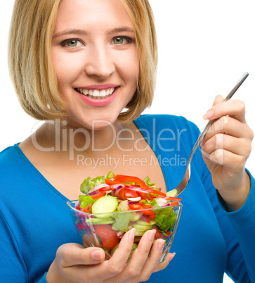 Young attractive woman is eating salad using fork