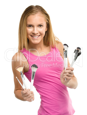 Teen girl is holding makeup brushes