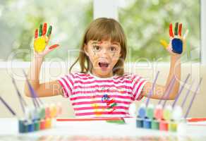 Portrait of a cute girl playing with paints