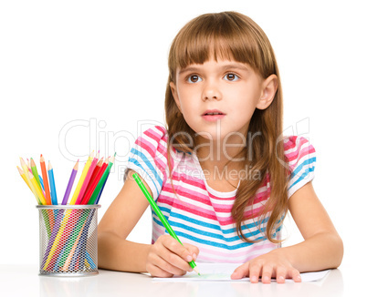 Little girl is drawing using pencils