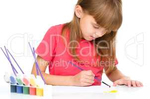 Little girl is painting with gouache