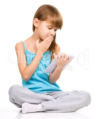 Young girl is using tablet while sitting on floor