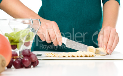 Cook is chopping banana for fruit dessert