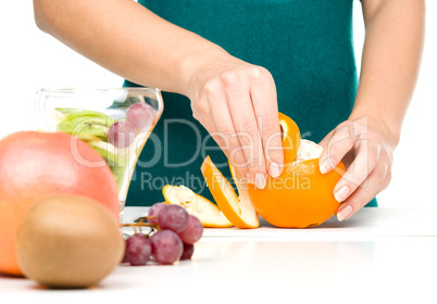 Cook is peeling orange for fruit dessert