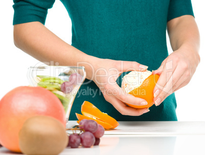 Cook is peeling orange for fruit dessert