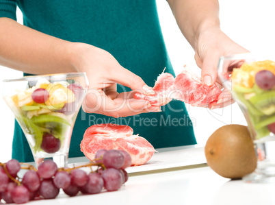 Cook is peeling grapefruit for fruit dessert