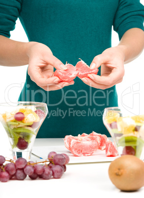 Cook is peeling grapefruit for fruit dessert