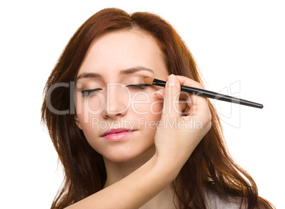 Stylist is applying eyeshadow for young girl