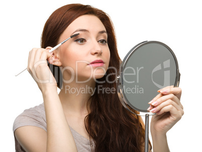 Young woman is applying eyeshadow