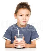Sad little boy with a glass of milk