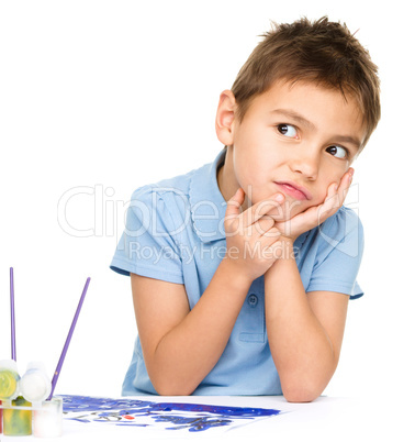 Young is daydreaming while drawing with paints