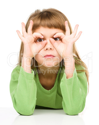 Happy little girl is showing glasses gesture