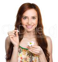 Young woman is tearing up daisy petals