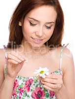 Young woman is tearing up daisy petals