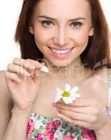 Young woman is tearing up daisy petals