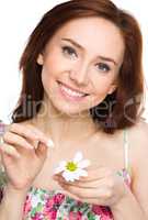 Young woman is tearing up daisy petals