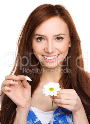 Young woman is tearing up daisy petals