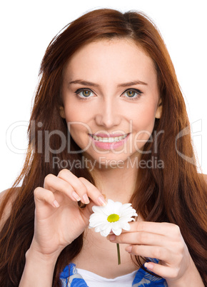 Young woman is tearing up daisy petals