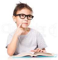 Young boy is daydreaming while reading book