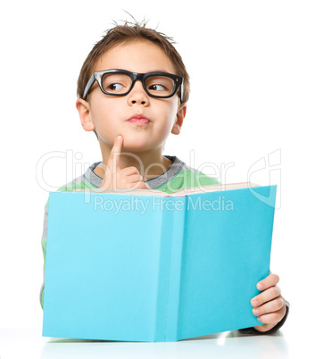 Young boy is daydreaming while reading book