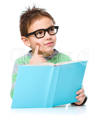 Young boy is daydreaming while reading book