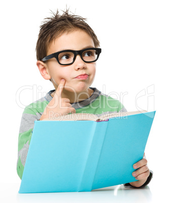 Young boy is daydreaming while reading book