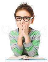 Young boy is daydreaming while reading book