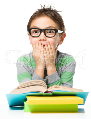 Astonished little boy is reading a book