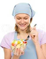 Young attractive woman is eating salad using fork