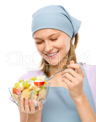 Young attractive woman is eating salad using fork