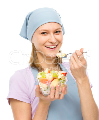 Young attractive woman is eating salad using fork