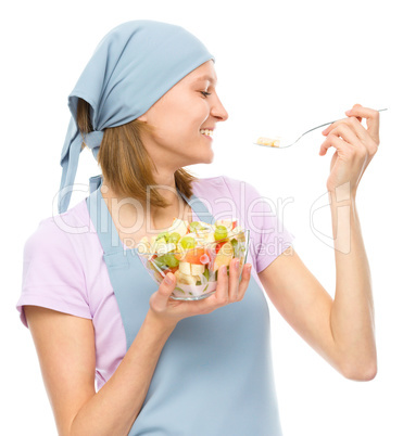 Young attractive woman is eating salad using fork