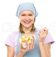 Young attractive woman is eating salad using fork