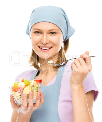 Young attractive woman is eating salad using fork