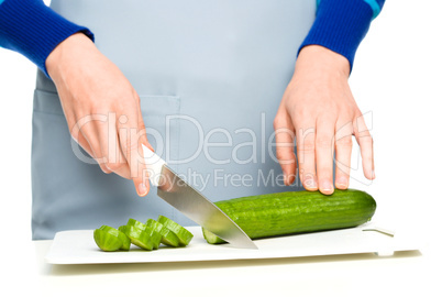 Cook is chopping green cucumber