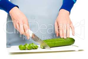 Cook is chopping green cucumber