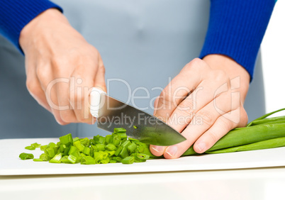 Cook is chopping green onion