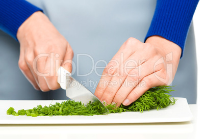 Cook is chopping green dill