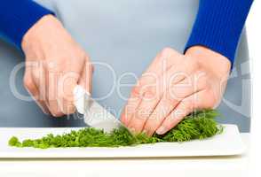 Cook is chopping green dill