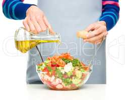 Cook is pouring olive oil into salad