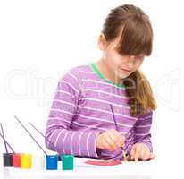 Little girl is painting with gouache