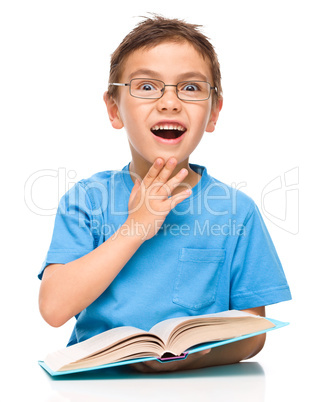 Astonished little boy is reading a book