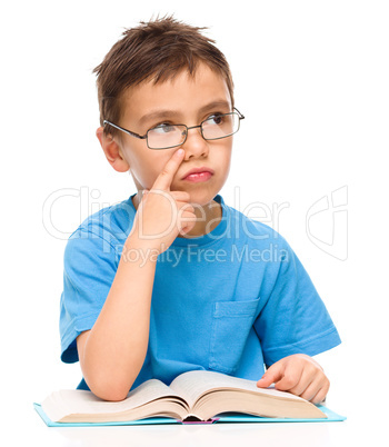 Young boy is daydreaming while reading book