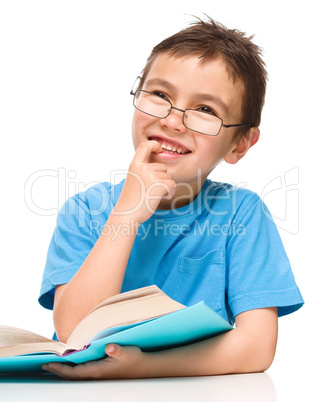 Young boy is daydreaming while reading book